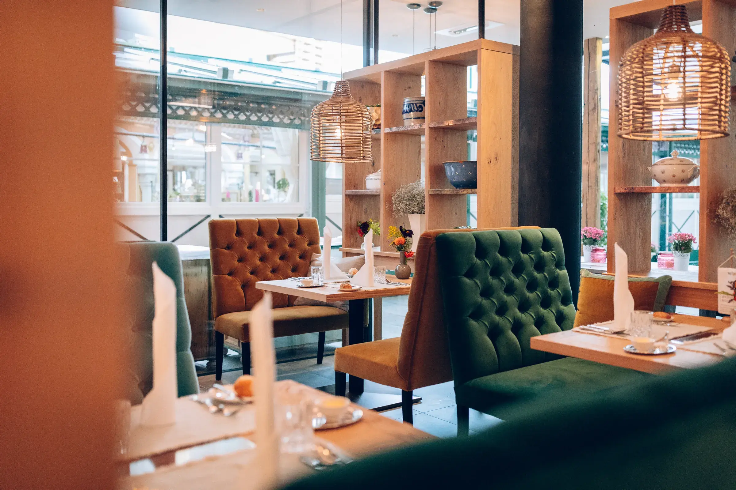 A-la-carte-Restaurant mit gepolsterten Samtstühlen, Rattanlampen und Holzregal mit Keramik im Alpenresort Schwarz