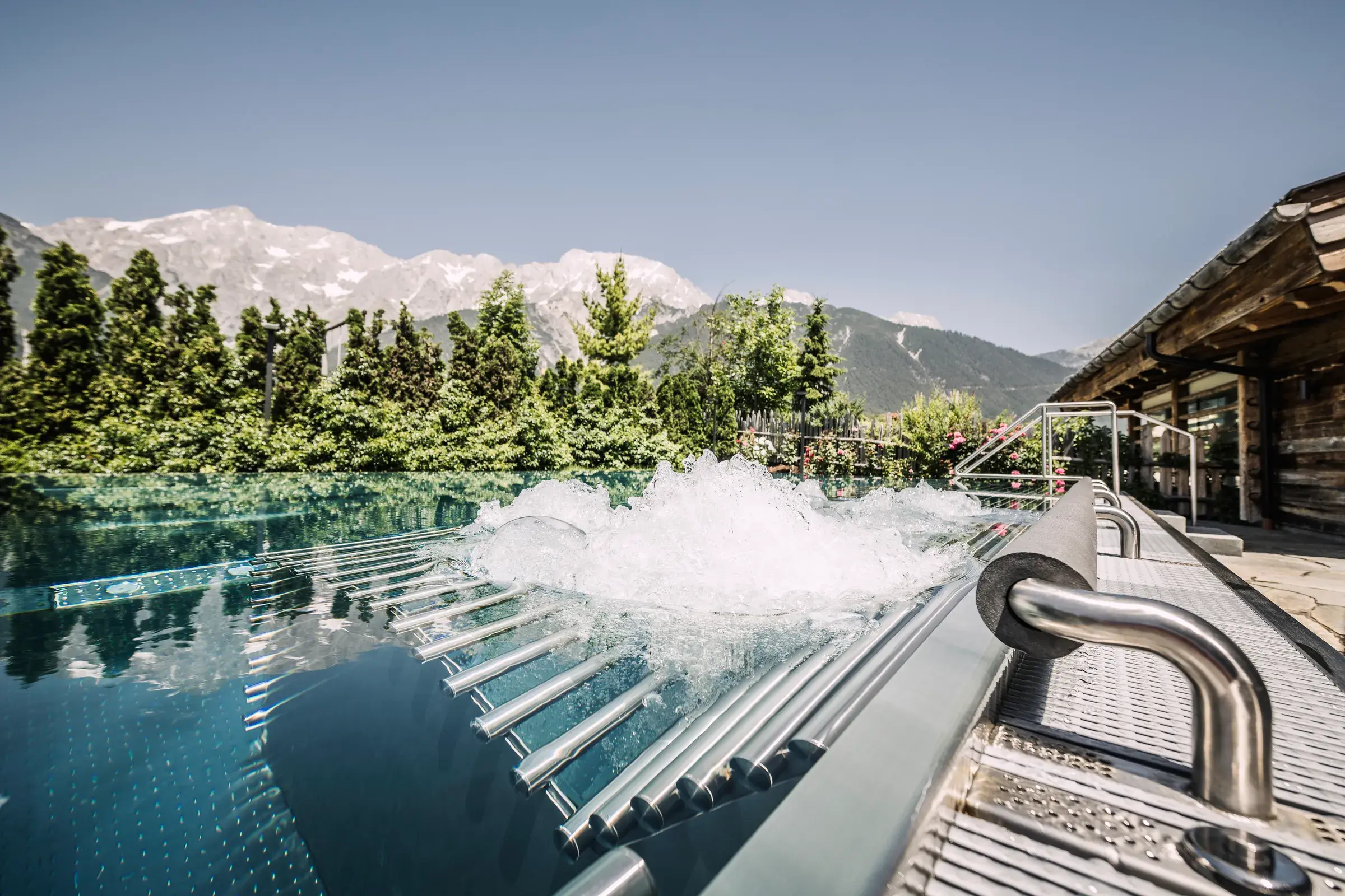 Sprudelnder Außenpool im Sommer mit Blick auf die Tiroler Berge im Alpenresort Schwarz