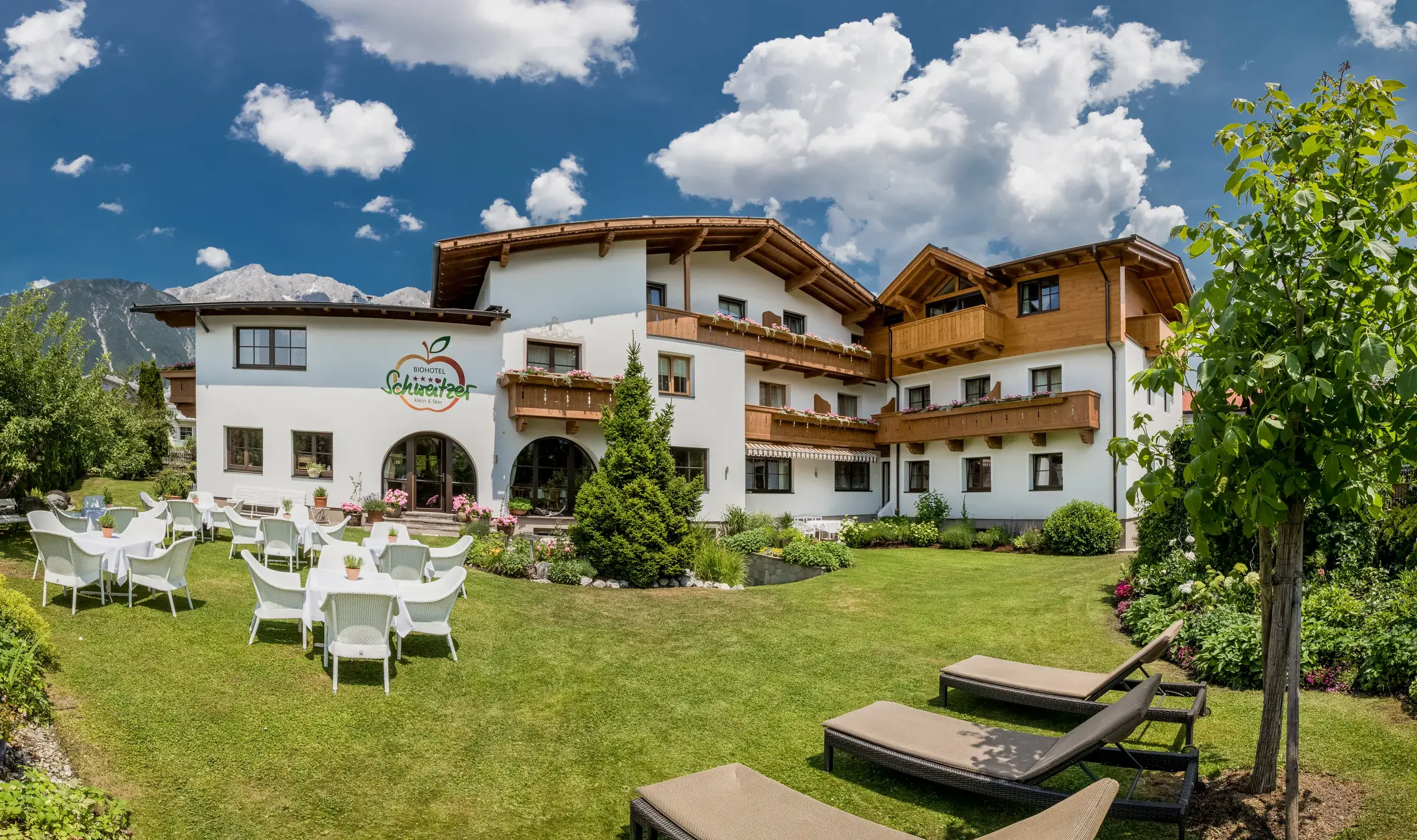 Südansicht des Biohotel Schweitzer in Mieming – Garten mit Sonnenliegen und Bergpanorama in Tirol