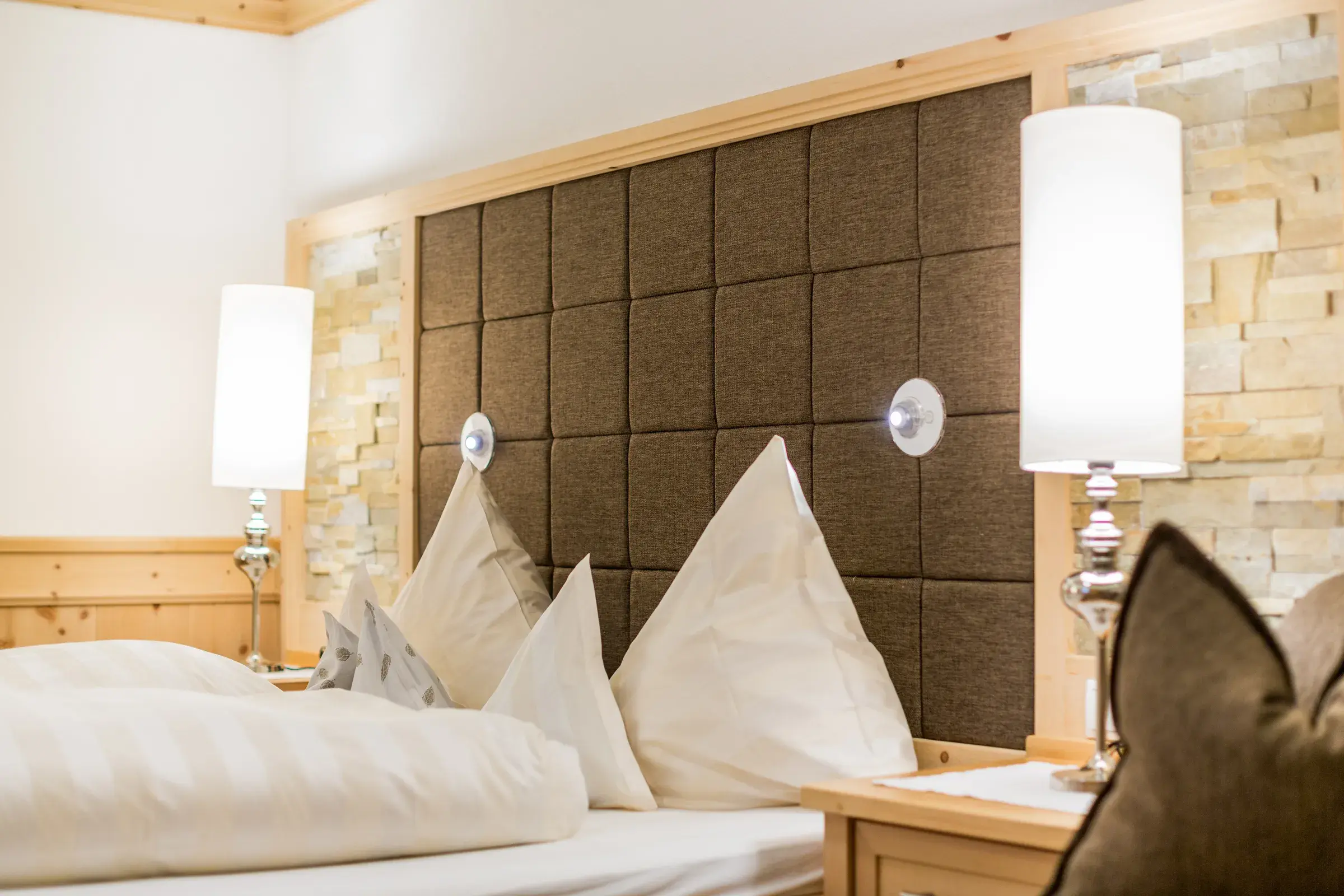 Doppelbett mit Zirbenholz und aufgestellten Kissen im Biozimmer Zirbe des Biohotel Schweitzer