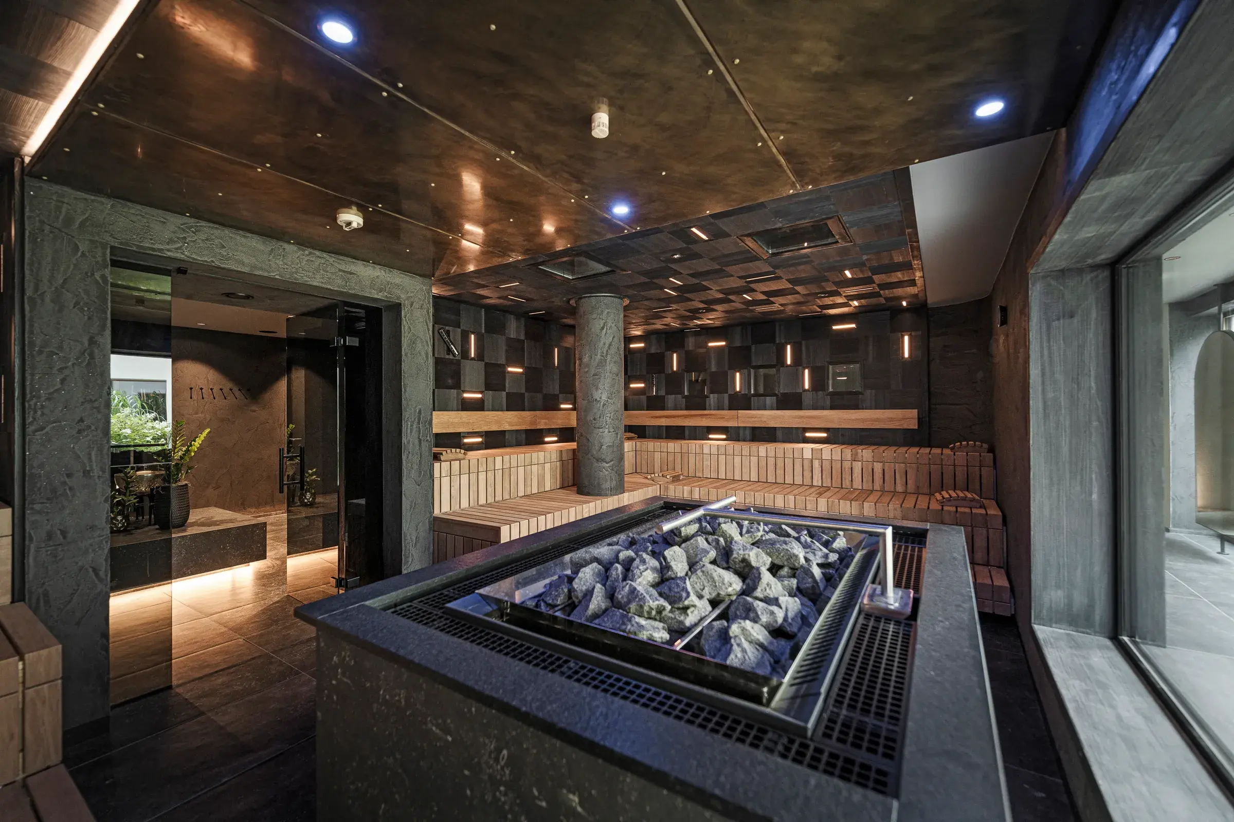 Stimmungsvolle finnische Sauna im Day Spa des Alpenresort Schwarz mit Saunaofen und stufigen Holzbänken